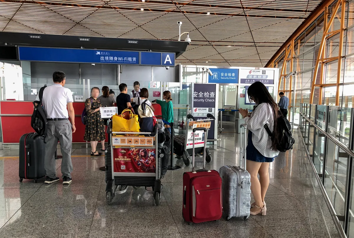 Travelers with luggage at a portable Wi-Fi rental counter in Beijing Capital Airport Terminal 3