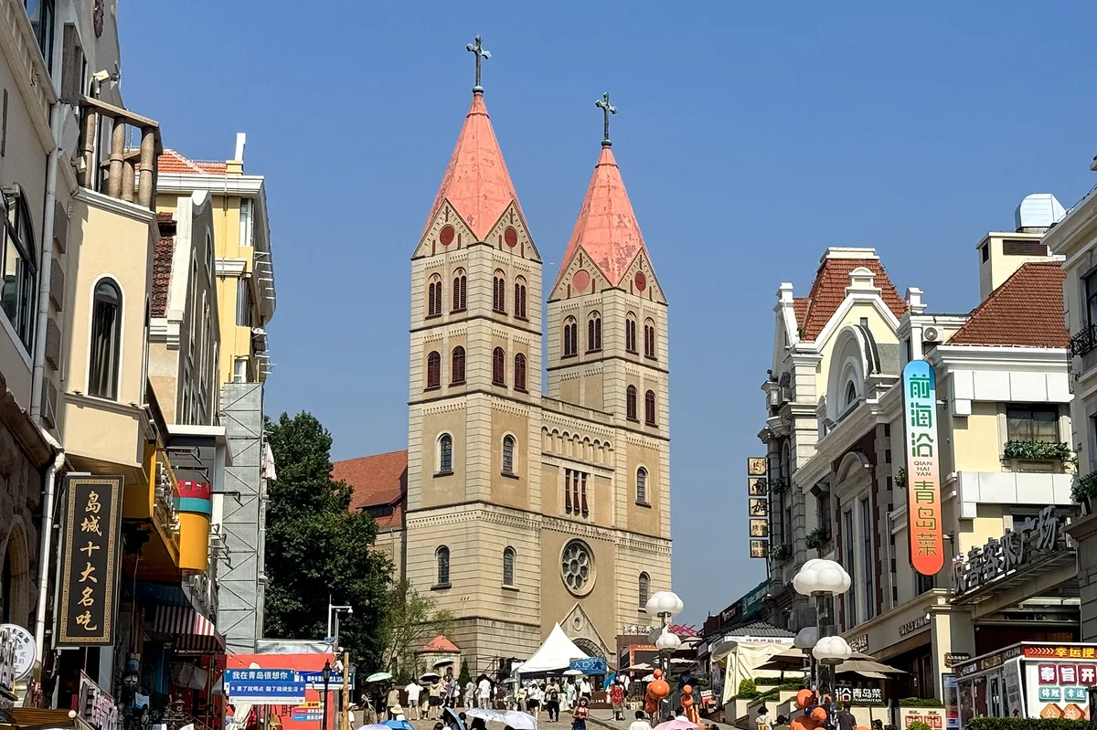 St. Michael's Cathedral twin towers at the end of a busy old-city street in Qingdao