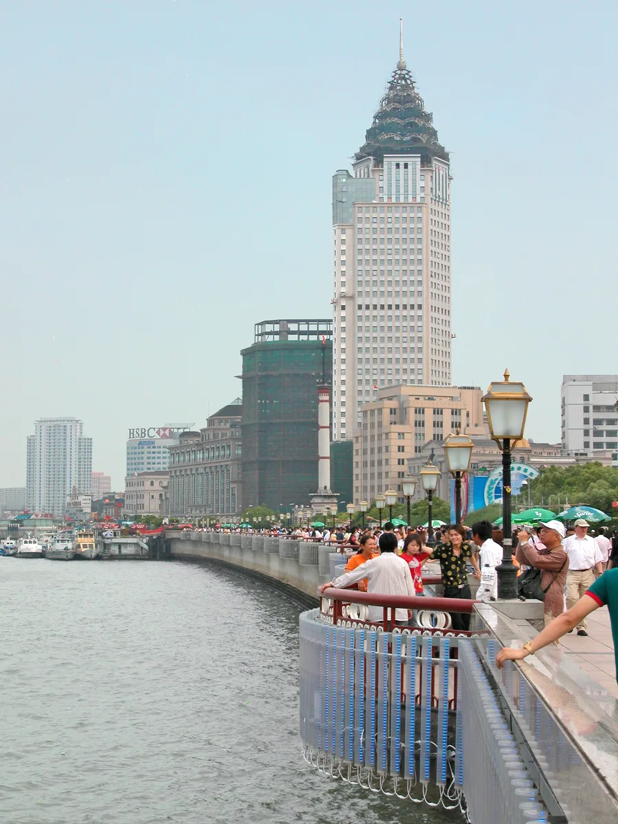 People walking the Bund promenade beside the Huangpu River in Shanghai