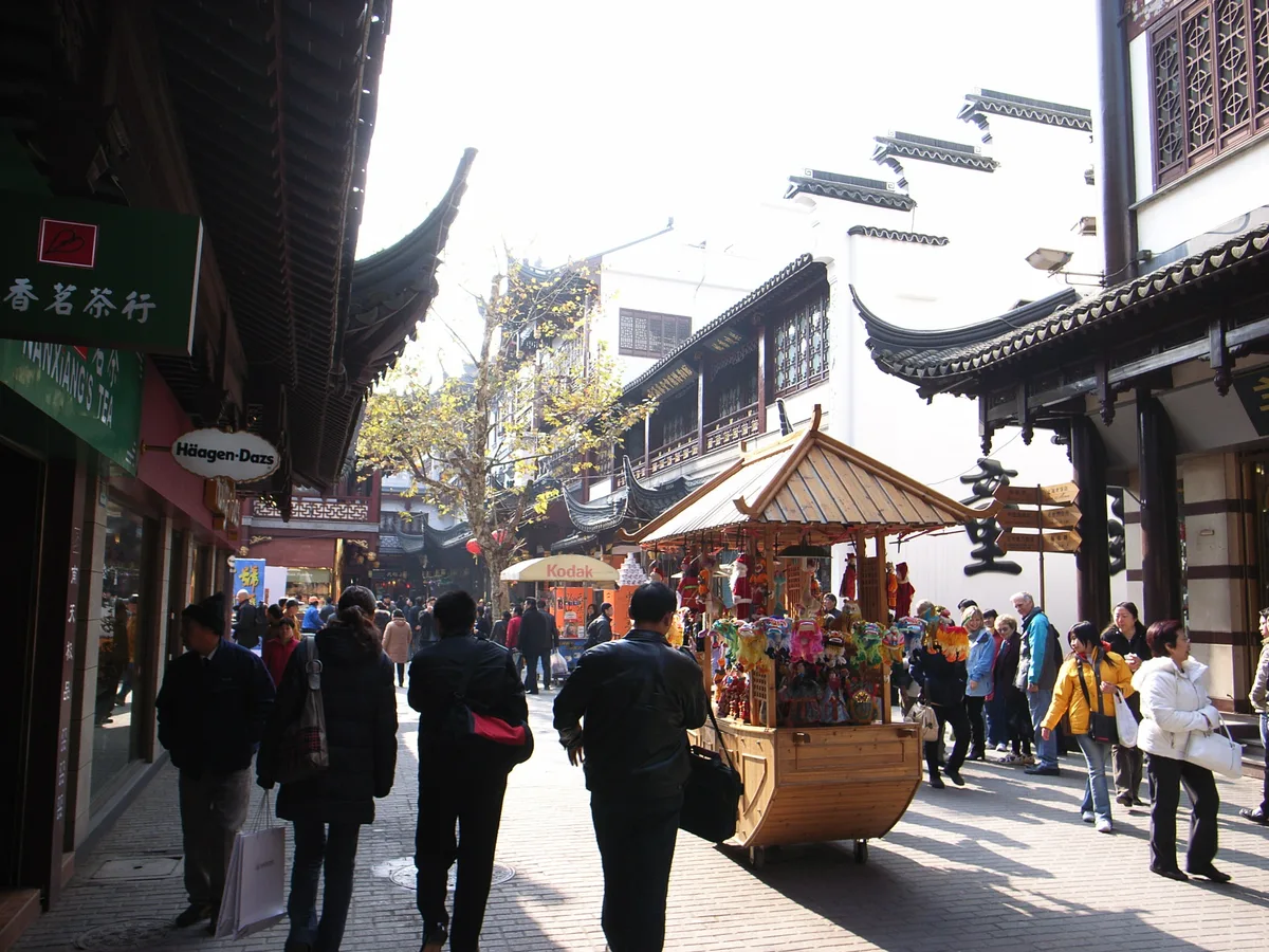A crowded old-city street of white walls and upturned eaves at the City God Temple in Shanghai