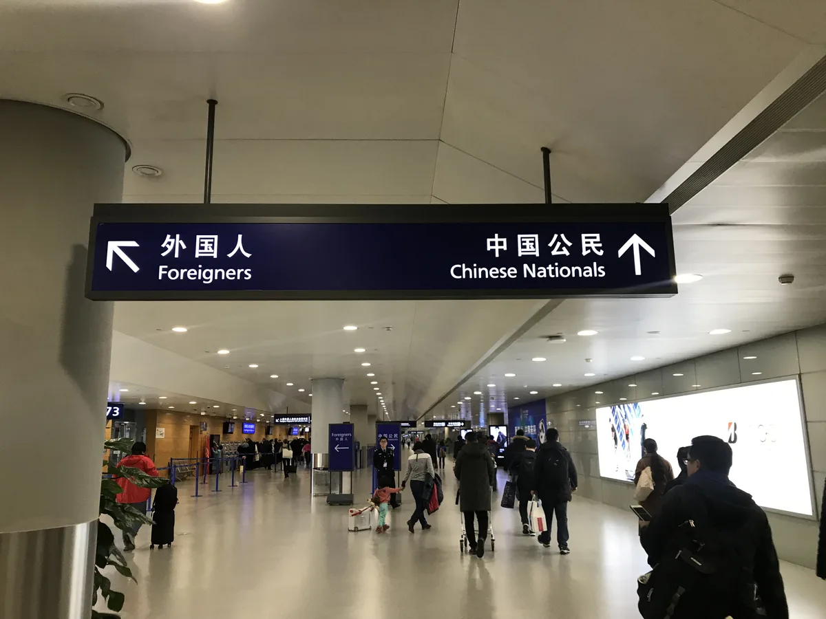 Overhead sign at Shanghai Pudong International Airport directing foreigners left and Chinese nationals ahead